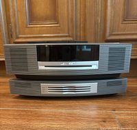 Front view of two stacked Bose Wave Music System units showing disc slot and speaker grilles