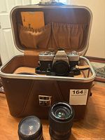 Minolta SR-T 201 camera, two lenses, inside leather lined carrying case with visible instruction manual and camera strap.