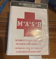 Front side of the DVD set box showing the title M*A*S*H, with a red cross and text indicating the complete series seasons 1-11 plus the Academy Award-winning film.