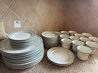 Full set spread on kitchen counter showing all dishes including stacked dinner plates, tea cups, saucers, salad and dessert plates with floral pattern