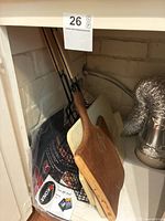 Grill baskets, pizza stone, wooden cutting board, and grill mat shown stored under a cabinet.