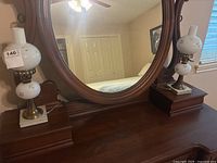 Two vintage electric hurricane lamps placed on a wooden dresser with mirror in background.