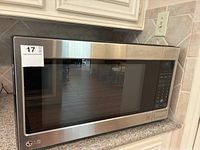 Front view of LG microwave showing stainless steel finish, large tinted glass door and branding.