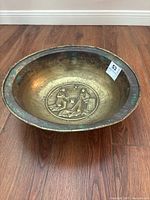 Top angle photo showing the oval brass bowl with sculpted figures at the center and wide rim with patina.