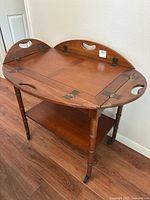 Full view of wooden Butler-style tea cart showing removable tray with handles and lower shelf on caster wheels.
