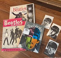 Three books featuring The Beatles with two visible covers and four black and white photo cutouts of band members