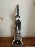 Front view of Bissell Cleanview Rewind Pet vacuum cleaner, showing upright design with handle and large clear dirt canister with label.