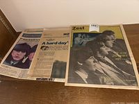 Photo showing three vintage newspapers featuring The Beatles including Zest edition and Weekend edition, spread on wooden floor.