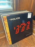 stack of vinyl records leaning against wood panel