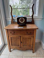 Antique oak wood hutch viewed from the front with the John Wanamaker clock on top, showing the drawer and cabinet doors closed.