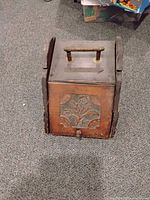 Front view of antique wooden box with detailed floral carving and metal handle