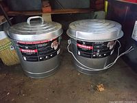 Two Behrens metal cans with locking lids and side handles, labels visible on front.