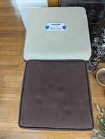 Top view of beige ottoman lid and detached brown fabric base.