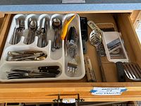 View of kitchen utensils in drawer organizer showing cutlery, garlic peeler, and some kitchen tools
