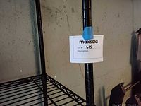 Close up of the corner post and metal wire shelf construction with MaxSold tag on shelving