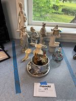 Wide view showing all figurines, vases, and animal figures arranged on a surface near a window