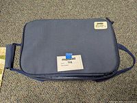 Blue Pyrex-branded fabric carrier with handle and zipper, used to transport the baking dish.