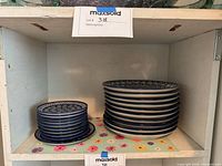 Two stacks of plates on shelf: smaller plates on left, larger plates on right