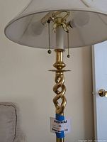 Close-up showing the twisted brass design, dual bulbs, and pull chains under the fabric shade