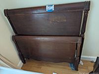 Photo of twin size solid wood headboard and footboard set leaning against wall, showing the rear and some wear marks.