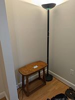 Full view of the floor lamp beside the wooden bench in a corner.