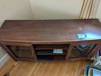 Top and angled view of wooden TV stand showing medium brown finish and minor surface wear.