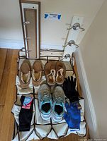 Used sneakers, slippers, gloves, and coat racks with shoe storage units arranged on floor and leaning against wall.