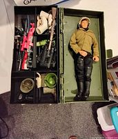 GI Joe action figure with weapons and accessories organized in green case