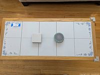 Top view of wooden coffee table showing tile inset with blue floral pattern and complementary coasters and tile samples on top.