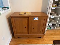 Front view of the wooden cabinet showing two doors and natural wood finish.