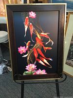 Full view of koi pond canvas print with 2-tone gold and brown wooden frame on display stand indoors.