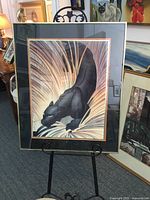 Full view of the panther print framed in black aluminum with triple matting, mounted on a display stand in an art gallery context.