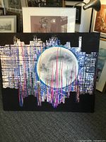 Front view of the large square mixed media painting with city skyline silhouette under a large moon and colorful vertical lines.