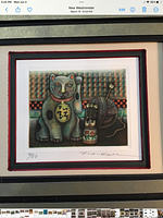Framed mezzotint etching showing a stylized lucky cat and multi-headed yarn doll in front of a geometric background, signed and numbered 21/50 on bottom left and signed on bottom right.