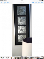 Full view of the tall, vertical framed Chinese calligraphy with four sections inside the two-tone silver and black frame hung on a wall.