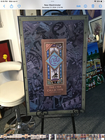 Full view of large grey aluminum framed poster titled 'The Coda Collection' displayed on a stand with surroundings indicating its size and condition.