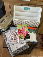 Photo showing cream-colored wooden desk organizer, metal letter holder, butterfly sticker sheet, and notebooks