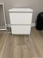 Front view of the white 2-drawer nightstand showing drawer handles and overall condition.