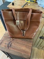 Front view of the large brown leather Lauren Ralph Lauren tote bag showing straps and hangtag.