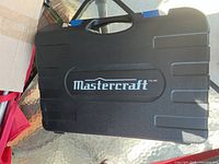 Closed black hard plastic case with Mastercraft logo and blue latches and handle.