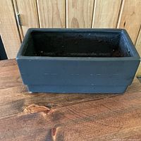 Front side view of the medium black rectangular planter pot showing soil residue inside.