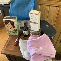 Various boxed and unboxed cosmetics, two bags, pink cloth on wood table