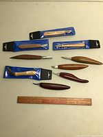 Full display of nine carving tools with wooden handles in various shapes and four tools in original blue packaging, showing size and variety.