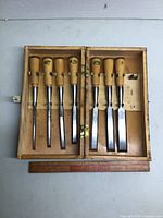 Full set of six Hoppe chisels with wooden handles in an open wooden case, showing one missing slot.