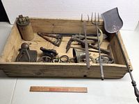 Top-down view showing the lot inside a wooden crate with two meat forks, door knockers, a buggy step, and other metal hardware.