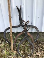 Photo showing three different sizes of heavier iron ice tongs arranged upright against a corrugated metal backdrop, with a measuring stick to indicate size.