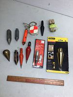 Full view of assorted plumb bobs and measuring tools laid out on a surface.