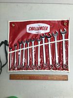 Full view of the 11 Proto Challenger combination wrenches in a red roll-up pouch, sizes 7 mm to 17 mm, laid out next to a wooden ruler for scale.