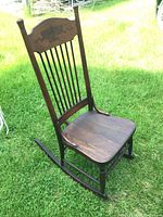 Front angle view of the wooden rocking chair showing the carved back and vertical slats.