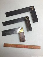 Three measuring squares on table with wooden Coca-Cola ruler for size reference